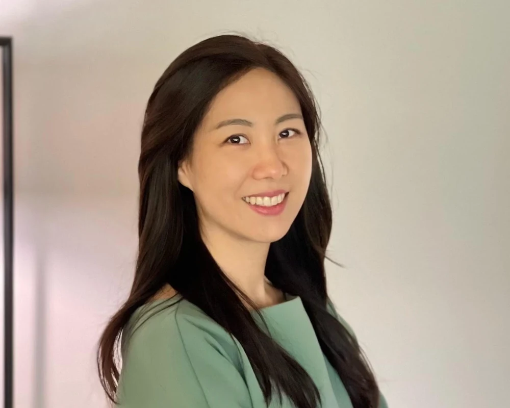 Jinkyung Lee, Korea Programs Coordinator at Startup Junkie Consulting, smiling in a sage green dress